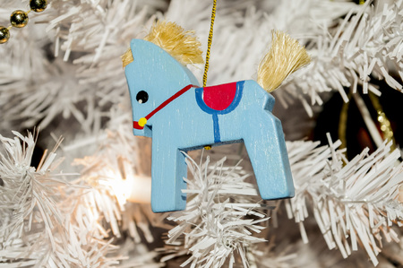A wooden rocking horse on a white Christmas tree.の写真素材