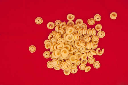 	Heap of italian pasta on red background