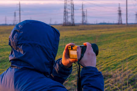 Photographer taking pictures of power lines at sunset. high quality photoの写真素材