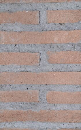 a stone wall red with grey cement and oriented in a vertical way