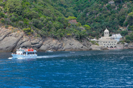 CAMOGLI, ITALY - JUILLET 16, 2019: A tourist ferry leaves the Abbey of San Fruttuoso; the church is located in a small bay and it can only be reached by sea.のeditorial素材