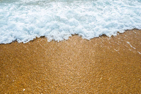 Soft blue ocean wave on clean sandy beach