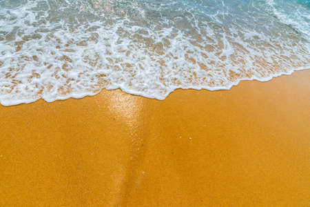 Soft blue ocean wave on clean sandy beach