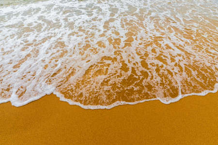 Soft blue ocean wave on clean sandy beach