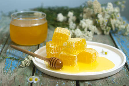 Honey in a glass jar and honey in honeycombs on an old wooden background