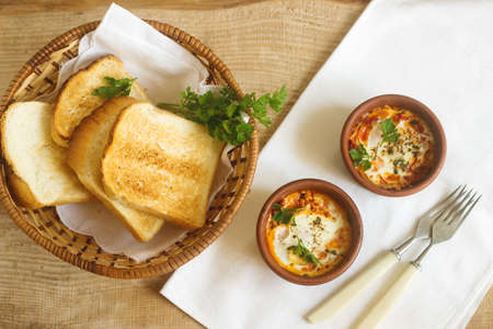 Breakfast with shakshouka in individual forms and bread toastsの写真素材