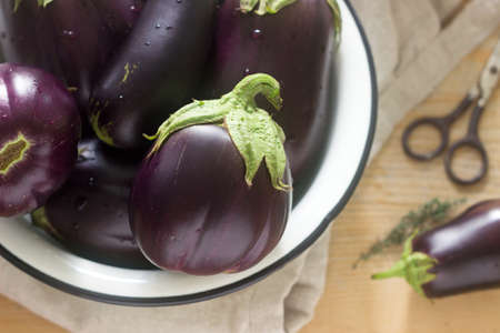 Aubergines in a bowl on a wooden table. Vertical. Selective focus.の写真素材