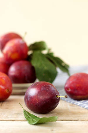 Plums in a plate on a wooden table, rustic style, selective focus.の写真素材