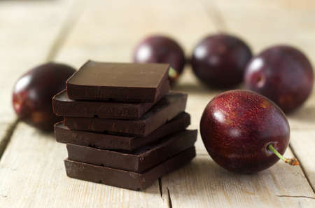 A stack of chocolate slices and plums on a wooden table. Rustic style, selective focus.の写真素材