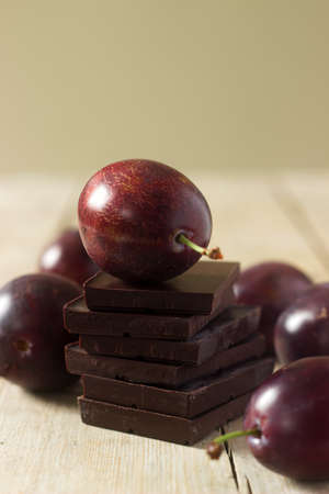 A stack of chocolate slices and plums on a wooden table. Rustic style, selective focus.の写真素材