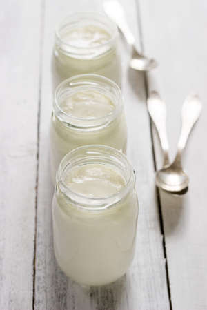 Homemade yogurt in a glass jar on a wooden table. Rustic style, selective focus.の写真素材