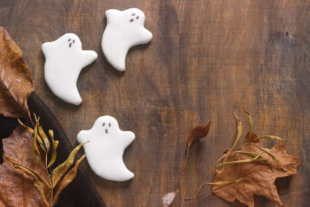 Gingerbread ghost for halloween, decorated with autumn leaves, on a wooden background. Selective focus.の写真素材
