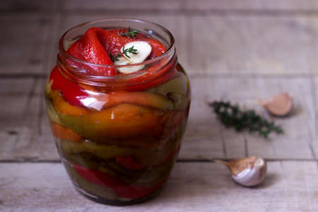 Baked pickled sweet pepper with garlic and thyme in a glass jar. Selective focus.の写真素材