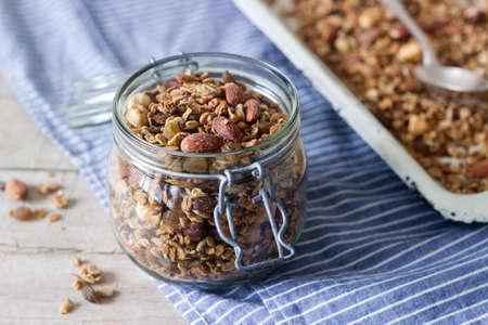 Homemade granola in a glass jar and on a baking sheet. Rustic style, selective focus.の写真素材