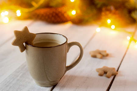 Cocoa or hot chocolate with cinnamon and gingerbread on a background with spruce branches, cones and garland. Bokeh effect, selective focus.の写真素材