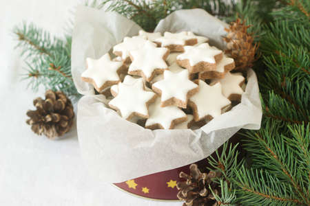 Cookies cinnamon star in a tin box on a background of fir branches and cones. Selective focus.の写真素材