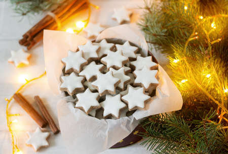 Cookies cinnamon star in a tin box on a background of cinnamon sticks, fir branches and cones. Selective focus.の写真素材
