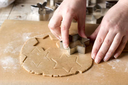 A woman rolls out the dough and cuts out the biscuits. Selective focus.