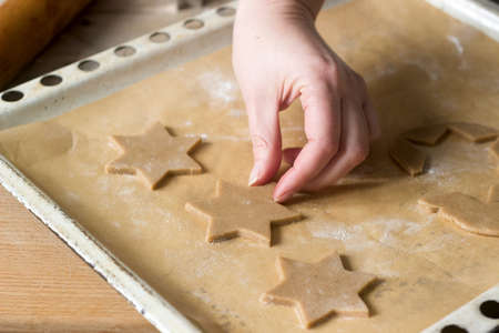 A woman rolls out the dough and cuts out the biscuits. Selective focus.