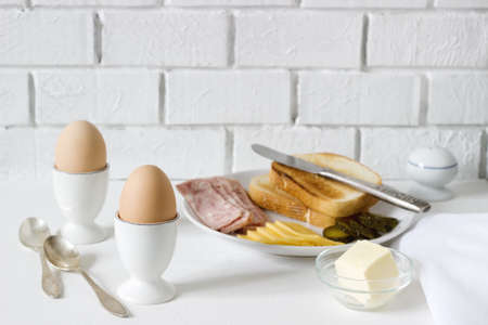 Breakfast with soft-boiled egg, bread toast, ham, cheese and canned cucumbers. Rustic style, selective focus.の写真素材
