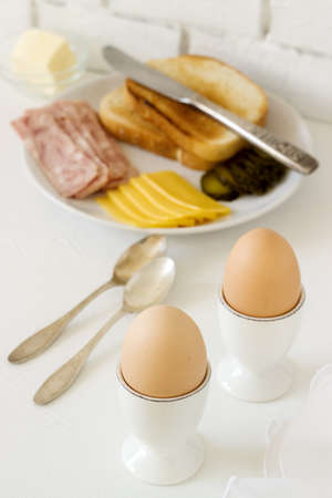Breakfast with soft-boiled egg, bread toast, ham, cheese and canned cucumbers. Rustic style, selective focus.の写真素材
