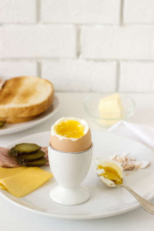 Breakfast with soft-boiled egg, bread toast, ham, cheese and canned cucumbers. Rustic style, selective focus.の写真素材