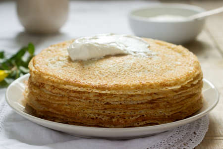 Delicate fishnet pancakes with sour cream. Selective focus.