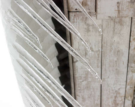Melted snow and large icicles hanging from the roof of the house. Selective focus.