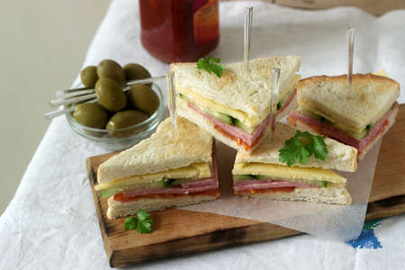 Sandwiches with sausage, meat, cheese and fresh vegetables on a table with olives and ketchup. Selective focus.の写真素材