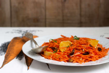 Juicy vitamin carrot salad with oranges, prunes and nuts. Rustic style, selective focus.の写真素材
