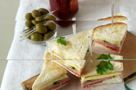 Sandwiches with sausage, meat, cheese and fresh vegetables on a table with olives and ketchup. Selective focus.の写真素材