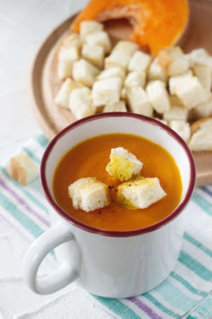 Delicate vegetable cream soup with pumpkin and croutons and slices of pumpkin on a light background. Selective focus.の写真素材