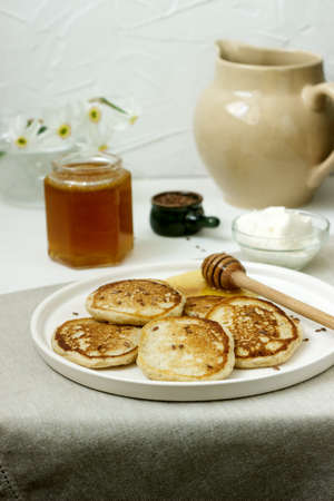 Linen pancakes served with honey and cream cheese on a light background. Rustic style, selective focus.の写真素材