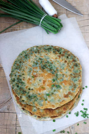 Homemade appetizing scallion pancakes and a bunch of green onions. Rustic style.