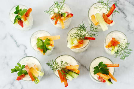 Snack in a glass with fresh cream and various vegetables on a light background. Selective focus.