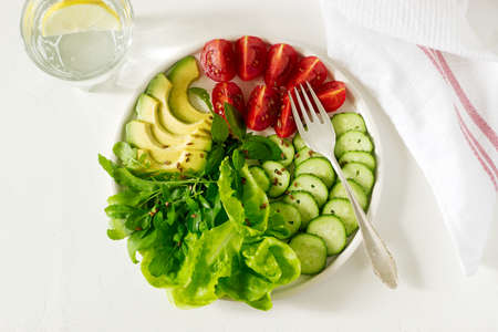 Vegetable salad with avocado and flax seeds on a light background, vegan food. Selective focus.