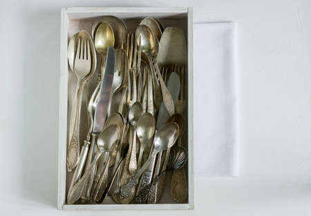 Vintage silver cutlery in a white wooden box on a white table. Rustic style, selective focus.の写真素材