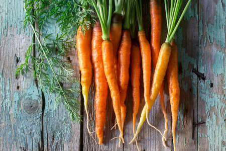 Fresh ripe carrots with tops on a wooden table. Selective focus.の写真素材