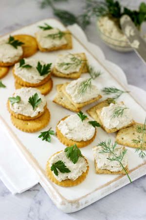 Snack from crackers and curd fish paste with herbs on a light background. Selective focus.