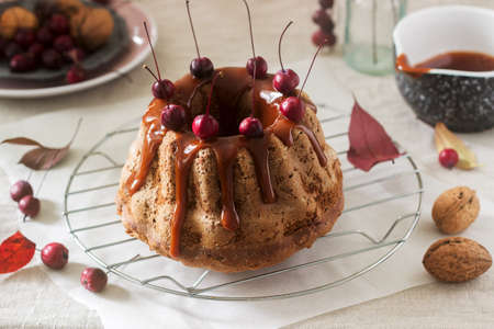 Apple pie with nuts, decorated with salted caramel and small red apples. Rustic style.