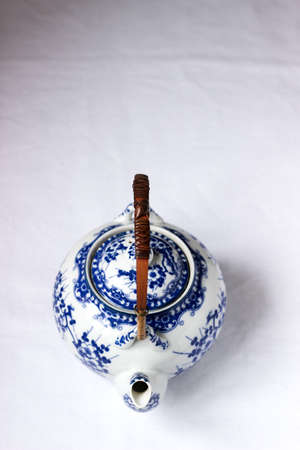 Chinese white porcelain teapot with bamboo handle and blue pattern on a white background.の写真素材