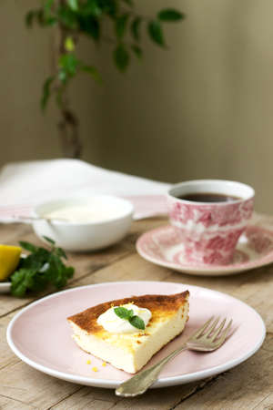 Healthy breakfast made from soft cottage cheese casserole with oatmeal and lemon zest, served with sour cream, mint and tea. Selective focus.の写真素材
