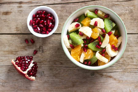 Salad of slices of various fruits and pomegranate seeds on a wooden background. Selective focus.の写真素材