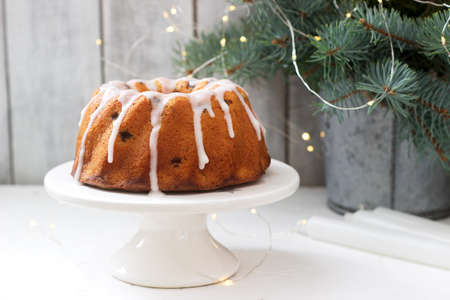 Pie with raisins and icing from powdered sugar on the background of fir branches and garlands....