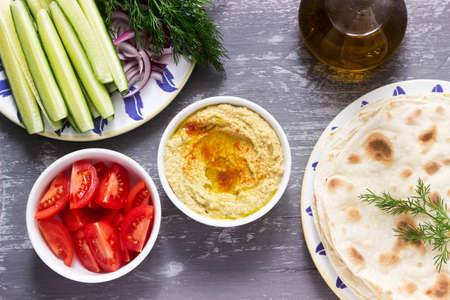 Vegan food, homemade hummus with flatbread, vegetables and olive oil on a concrete background. Selective focus.の写真素材