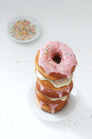 Homemade donuts decorated with colored icing and colored sugar on a light background. Selective focus.の写真素材