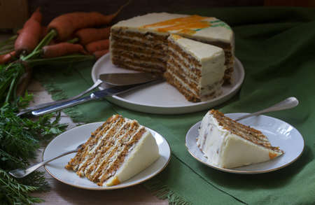 Carrot cake, pieces of cake with curd cream and carrots on a wooden background. Rustic style.