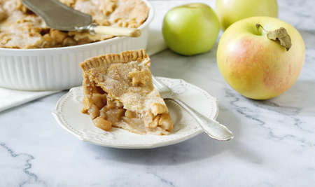 A traditional American apple pie decorated with stars and sugar, apples and cinnamon on a light background. Selective focus.の写真素材