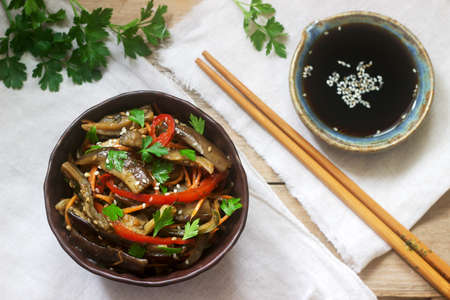 Oriental style vegetable salad with eggplant, soy sauce and chopsticks on a wooden table. Rustic style, selective focus.の写真素材