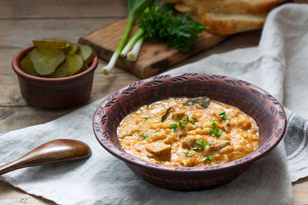 Bean and meat stew, served with pickles, bread and garlic. Rustic style, selective focus.
